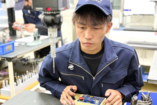 私は品質管理課で製品の寸法測定を担当しています。
三次元測定機やノギス、マイクロメーターといった測定機器を使い、製品が図面通りに正確に加工されているかを一つひとつ丁寧に確認しています。
わずかな不具合も見逃すことができない細かな作業が多い分責任も大きいですが、それだけに品質を支えるという誇りを持って仕事に取り組んでいます。
ときには難しさを感じることもありますが、日々の積み重ねを通じて自分の成長を実感できる点にやりがいを感じています。
